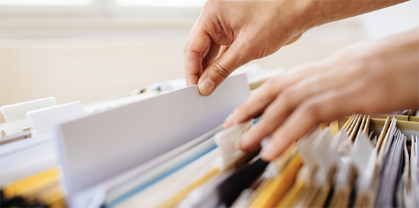 Photo of a pair of hands filing some papers in a drawer.