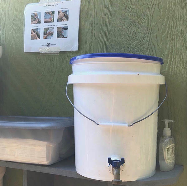 A mobile handwashing station made out of a five gallon bucket.