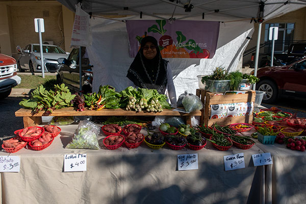 This market display uses red plastic baskets and laminated, handwritted signs to display greens, beans, eggplant and potatoes.