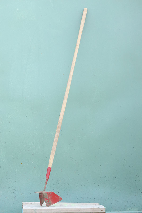 Photo of a zipper tool, a gardening tool with a head that is narrow on one side and wide on the other, used to dig and close a trench for planting.