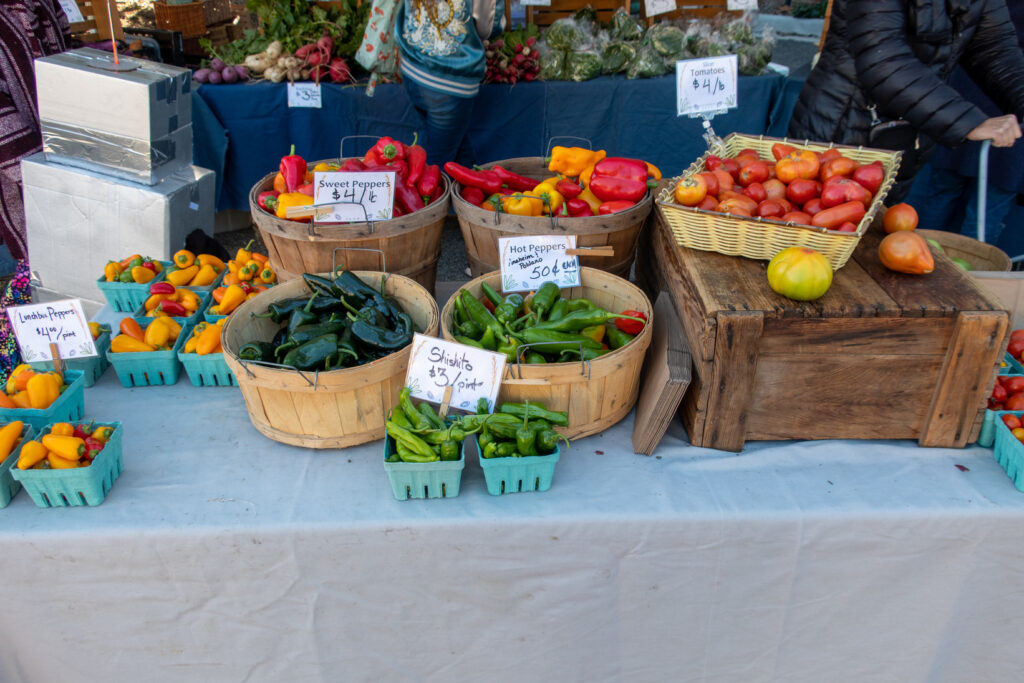 Produce for sale at a farmers' market with price signs.
